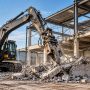 Commercial building being prepared for demolition with an excavator removing structural materials